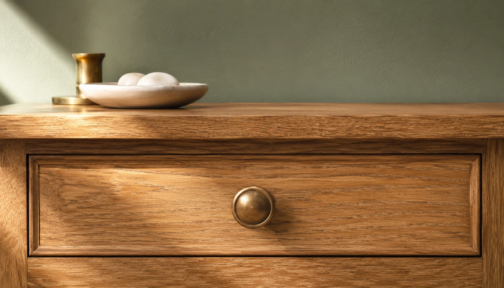 Sage green bedroom with aged brass hardware drawer pulls and lighting accents