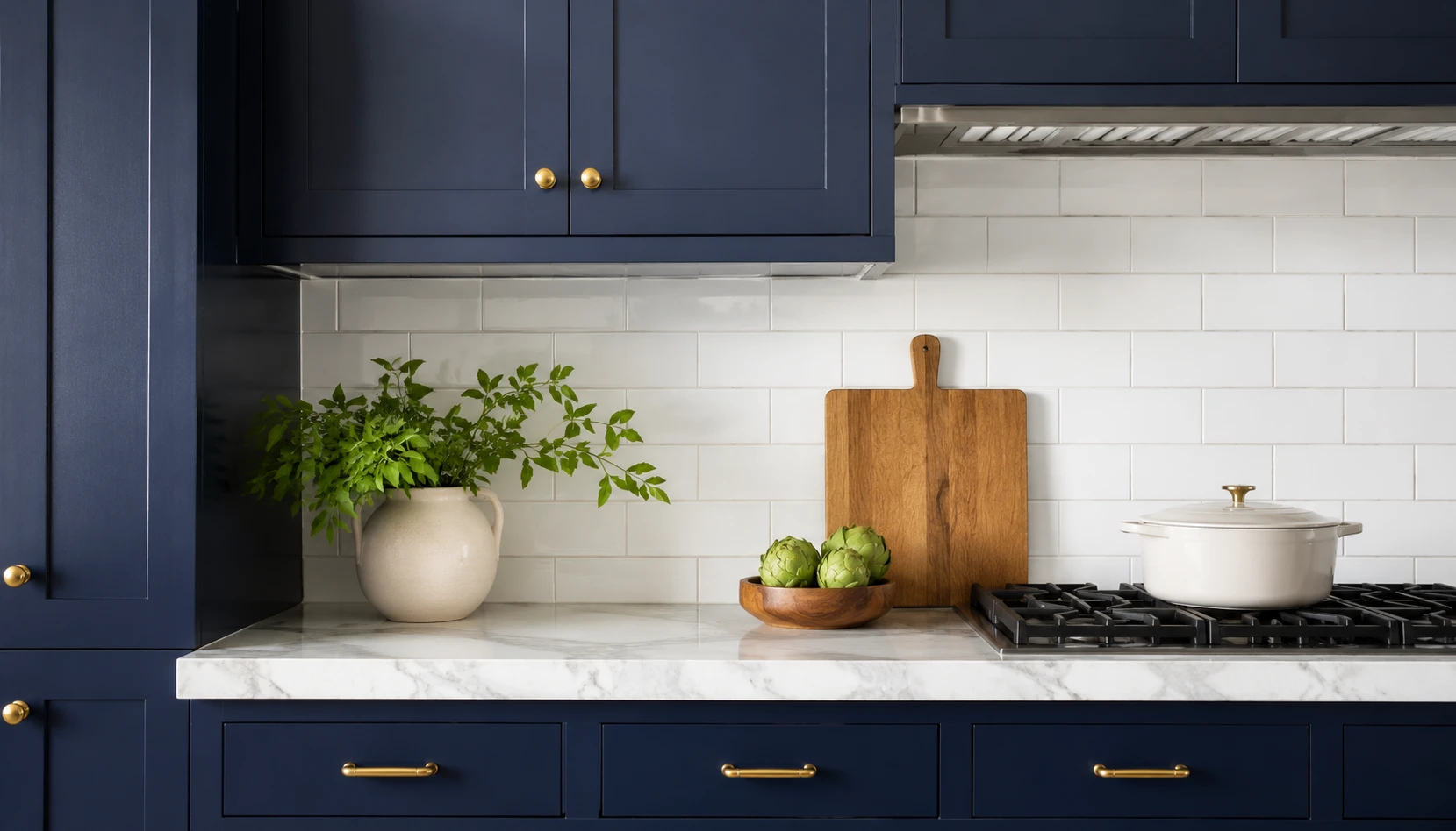 Navy blue kitchen cabinets with white marble countertop and subway tile backsplash