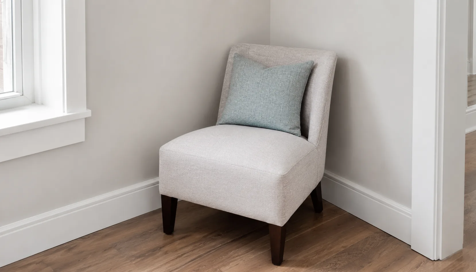 Single accent chair angled into a room corner with a small side table and warm lamp light
